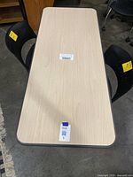 Top view of the rectangular beige wood finish table with a sticker on surface.