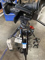 Panasonic camcorder mounted on tripod with accessories on floor