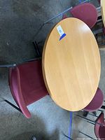 Top-down angle view showing the round wooden table and two red fabric chairs with metal frames.