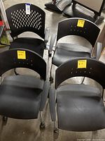 Four black Safco office chairs from front and top view showing seating surface, backrest with ventilation holes, armrests, and leg casters.
