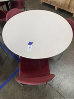 Top-down view showing round white tabletop and red chairs arranged around it.