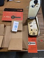 Top-down view of open empty record player casing, original box with branding, and instruction manual alongside.