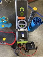 Top-down view of the workout bench, dumbbells, resistance bands, foam roller, and exercise mat arranged on concrete floor