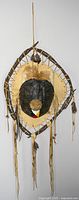 Front view of large Ojibwe dream catcher showing teardrop frame wrapped with deer hide and twigs, central snapping turtle shell with painted medicine wheel, rabbit fur and feathers.