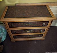 Front view of antique dresser showing three drawers with decorative painted panels and floral details, light wood frame and dark vignette top panel.