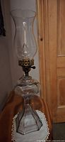 A full view of a vintage oil lamp converted to electric, featuring original multi-faceted glass base, brass burner assembly, and a new glass chimney.
