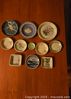 Top view of nine small china plates in assorted sizes and designs laid on a wooden surface.