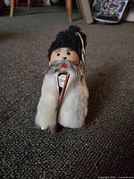 Photo shows a small 1950s shepherd doll made with leather and fur, labeled 'Tannimpex'. The doll is dressed in a furry white coat and black hat, holding a wooden staff.
