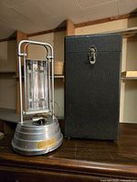 Photo showing the Sun-Kraft ultraviolet health lamp and its black textured carrying case side by side on a wooden surface.