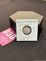 Photo of the coin in protective paper holder with label 'NEWFOUNDLAND 10 CENTS 1917'.