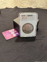 Coin housed in a clear protective capsule showing handwritten date 1939.