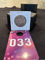 Photo of the 1941 Canadian 50 cent silver coin in a white cardboard holder with black box in background and auction tag visible.