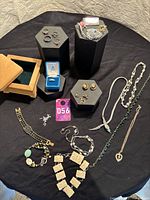 Overall assortment of jewelry including rings on display pedestals, necklaces, bracelets, brooch, loose stones, wooden box and watch