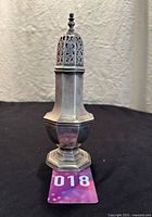 Full front view of English octagonal silverplate sugar shaker showing entire piece and base with the numbered tag 018