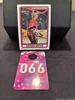 Photo of the hockey card standing up against a black background with numbered tag '066' in front.