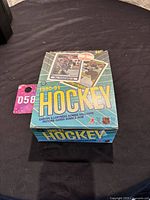 Photo of full unopened box of 1990-91 O-Pee-Chee Canada NHL Hockey cards with visible box top and edges showing wear consistent with age.