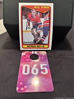 Additional front image of the card with a key tag showing number 065 placed in front, on black background.