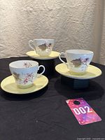 Three Shelley Bramble pattern cups and saucers displayed with floral design, yellow saucers, and gold trim details.