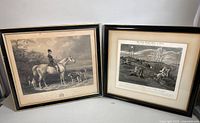 Photo of two framed monochrome etchings showing equestrian and hunting scenes, arranged side by side on a white surface.