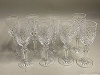 Eight Waterford crystal glasses arranged in two rows on a flat surface, showing uniform style and condition.