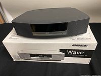 Bose Wave Music System III in graphite on top of original box showing front and top view.