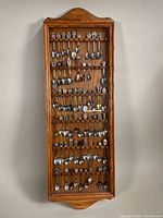 Full view of closed wooden wall display case filled with rows of collectible spoons.