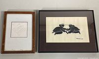Two framed Inuit artworks side by side on a surface, showing the size difference and frame types.