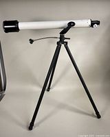 Full view of vintage TASCO adjustable astronomical telescope mounted on black tripod stand.