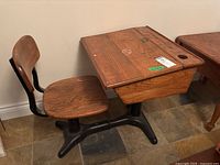 Side angle showing antique wooden desk with attached seat, natural wood finish, metal frame base, and storage compartment.