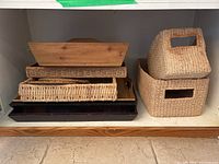 Front view showing stacked woven baskets and wooden trays on a shelf.