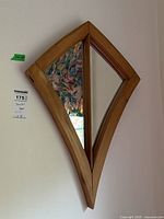 Full view of the wooden framed mirror showing its diamond shape and size tag of 27x18 inches.