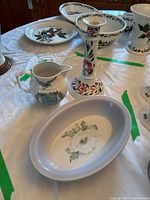 Photo showing the jug, candlestick, and oval bowl on a table with other ceramic pieces in background