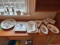 Wide view of bench showing round divided dish, square and rectangular platters, and additional pieces under window