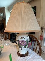 Full image of the Portmeirion ceramic table lamp with beige pleated lampshade on a wooden base, floral and butterfly design on the ceramic body.