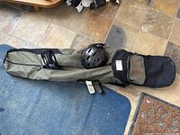 Olive green and black Burton soft snowboard case laid out on floor