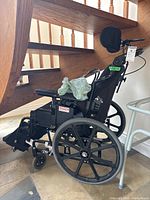 Side view of black Power Plus Mobility STP wheelchair showing large rear wheels, footrests, headrest, and ROHO cushion on seat.