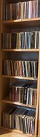 Wooden shelves filled with multiple rows of music CDs in jewel cases, assorted artists and genres, shelf labelled #4 and #5 visible.