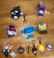 Photo showing the full 11 item lot with various keychains and bag charms on a wooden surface.