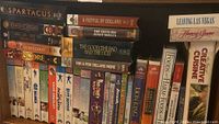 DVD movies stacked on a shelf alongside hardcover cookbooks including 'Leaving Las Vegas' and 'Creative Cuisine'