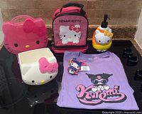 Full display of Sanrio items including containers, lunch bag, soap dispenser, Kuromi t-shirt, and My Melody toy on a countertop