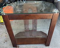 Front view of wood and glass TV stand unit with large glass top, wooden drawer below, and glass shelves.