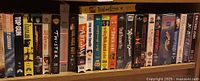 Shelf of 21 VHS tapes showing colorful movie spine covers including Top Gun and Twister
