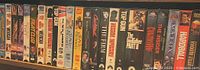 Front view of a selection of VHS movie tapes in their cases showing titles such as Fight Club, Pulp Fiction, Top Gun, The Godfather Part II, The Insider, The Matrix, and Hardball.