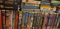 Front view of a shelf with multiple VHS tapes featuring movie and animated film titles.