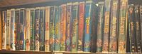 Full row of VHS and DVD cases on shelf, featuring titles including Disney movies, sports comedies, and other family films.