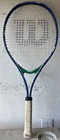 Full view of the Wilson tennis racket showing frame color, grip and string pattern with 'W' logo.