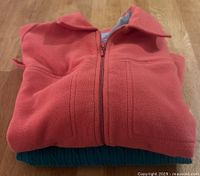 Orange fleece zip-up jacket folded, showing front and collar