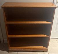 Front and side view of wood bookcase showing three shelves and wood grain detail.