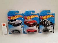 Photo of three new in box Hot Wheels cars: silver Ferrari Testarossa, red Honda Civic Type R, black & silver 1933 Ford Coupe, arranged side by side with blue Hot Wheels backing cards.