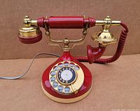 Front view of the 1950s retro rotary dial phone showing red body and gold handset with rotary dial.